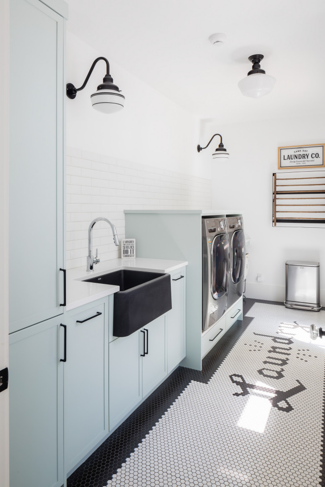 Inspiration for a small farmhouse utility room in Vancouver with flat-panel cabinets, blue cabinets, white splashback, porcelain splashback, white walls, a side by side washer and dryer, white floors and white worktops.
