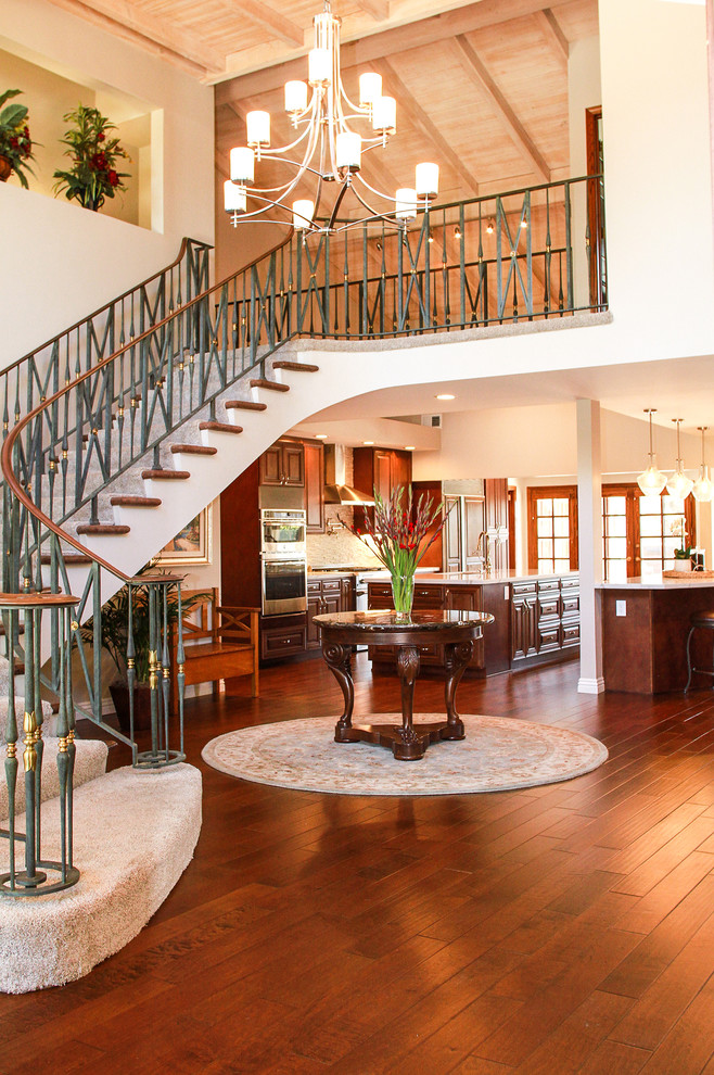 Kitchen - large transitional medium tone wood floor and brown floor kitchen idea in Orange County with a double-bowl sink, raised-panel cabinets, brown cabinets, quartzite countertops, white backsplash, stone tile backsplash, stainless steel appliances and two islands