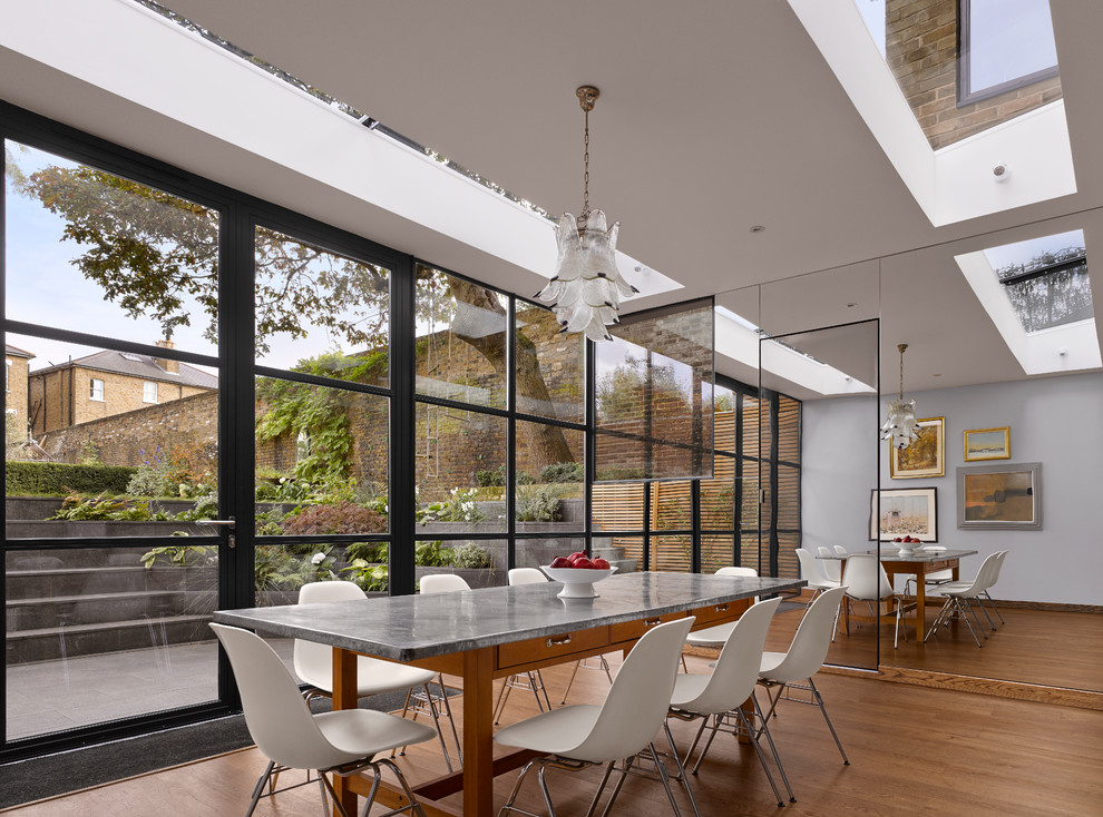 Photo of a contemporary dining room in London with grey walls and medium hardwood floors.