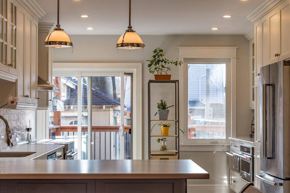 Eat-in kitchen - mid-sized transitional u-shaped eat-in kitchen idea in Toronto with a double-bowl sink, shaker cabinets, white cabinets, white backsplash, stainless steel appliances and a peninsula