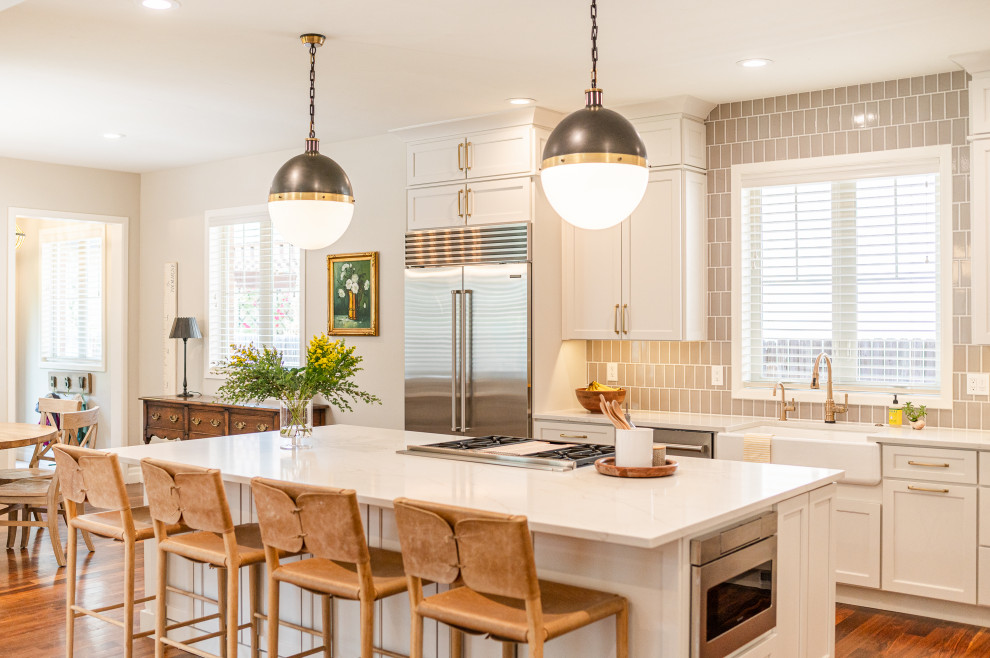 Inspiration for a large transitional l-shaped dark wood floor and brown floor open concept kitchen remodel in Denver with a farmhouse sink, shaker cabinets, beige cabinets, quartz countertops, beige backsplash, ceramic backsplash, stainless steel appliances, an island and white countertops