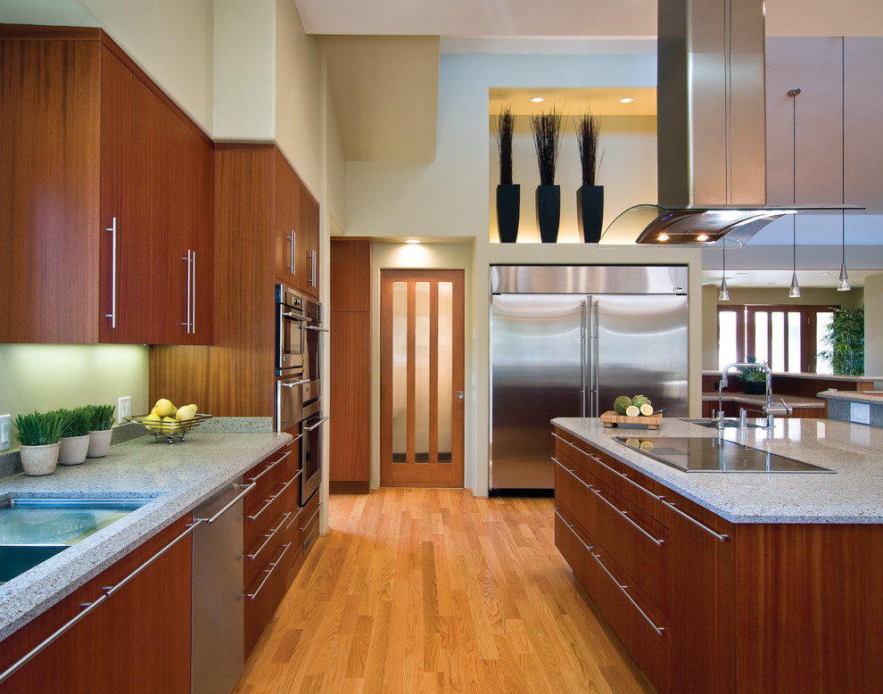 Large contemporary kitchen in Seattle with flat-panel cabinets, an undermount sink, medium wood cabinets, recycled glass benchtops, stainless steel appliances, medium hardwood floors and with island.