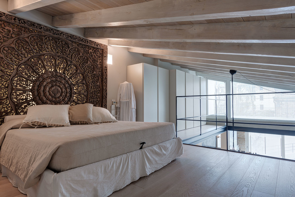 Inspiration for a large modern master bedroom in Milan with white walls and light hardwood floors.