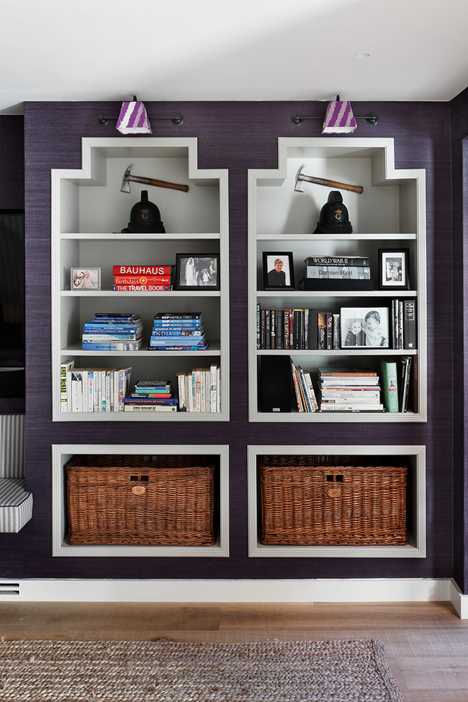Contemporary family room in London with a library, purple walls and light hardwood floors.