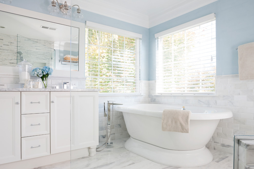 Inspiration for a timeless white tile and stone tile freestanding bathtub remodel in DC Metro with recessed-panel cabinets, white cabinets and blue walls