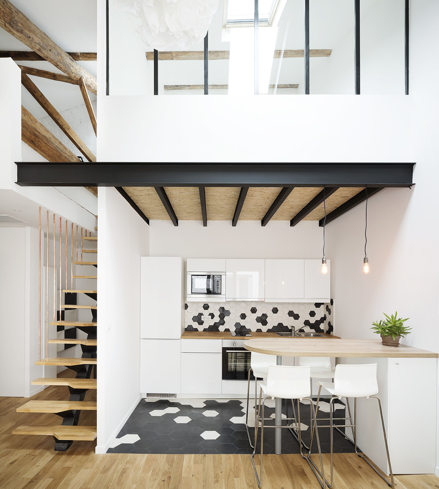 Photo of a mid-sized scandinavian single-wall eat-in kitchen in Montpellier with a drop-in sink, wood benchtops, multi-coloured splashback, ceramic splashback, white appliances, ceramic floors, a peninsula and flat-panel cabinets.