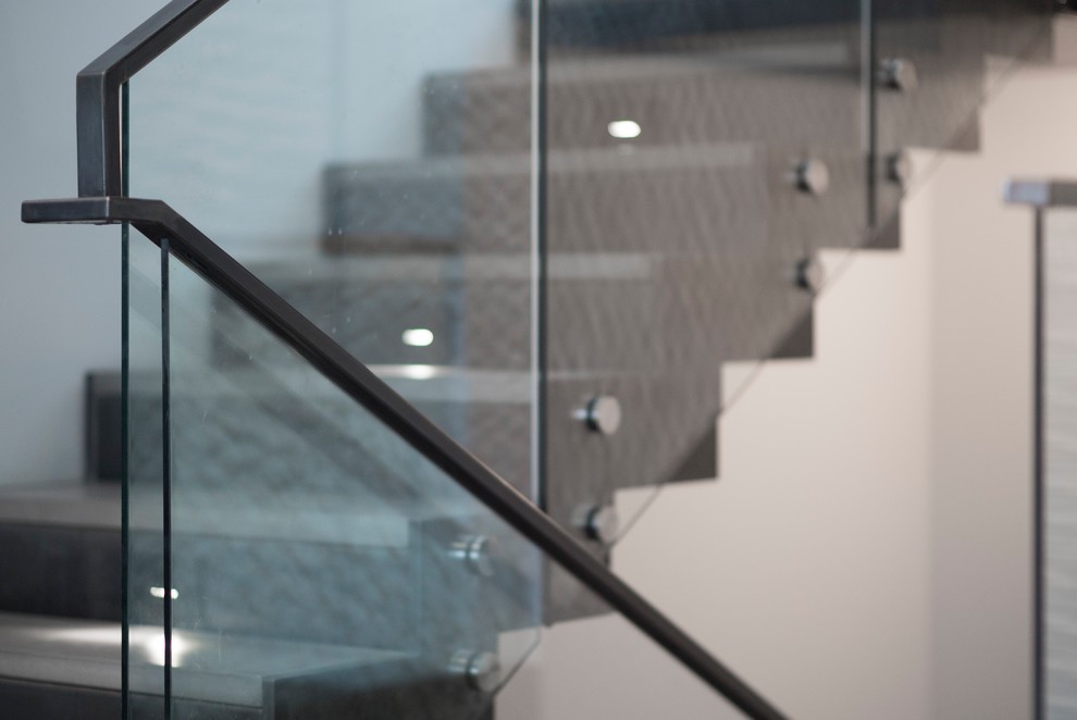 This is an example of a mid-sized contemporary concrete u-shaped staircase in Salt Lake City with metal risers and glass railing.
