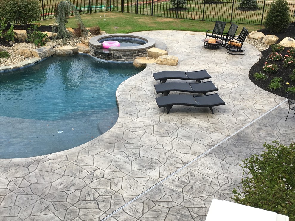 Expansive contemporary backyard custom-shaped pool in Philadelphia with stamped concrete.