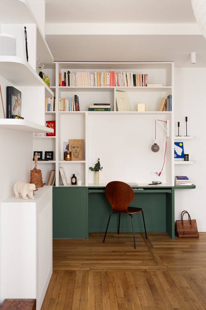Large contemporary home office in Paris with green walls and light hardwood flooring.
