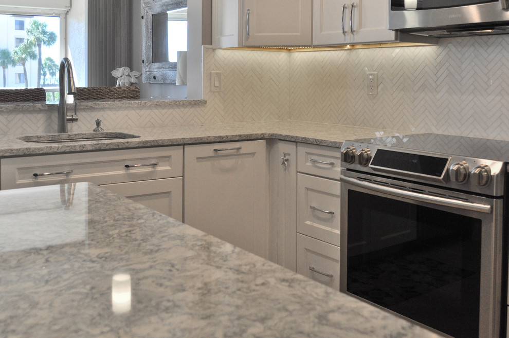 Example of a mid-sized transitional u-shaped eat-in kitchen design with an undermount sink, shaker cabinets, white cabinets, quartz countertops, white backsplash, marble backsplash, stainless steel appliances and no island
