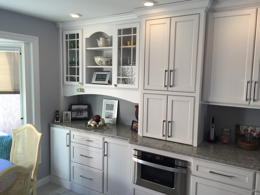 Inspiration for a large transitional l-shaped porcelain tile and gray floor eat-in kitchen remodel with an undermount sink, shaker cabinets, white cabinets, granite countertops, stainless steel appliances and no island