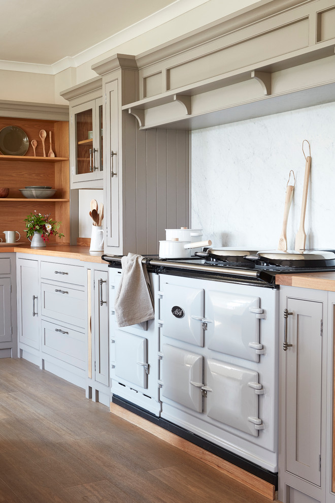 Design ideas for a large country l-shaped separate kitchen in London with an integrated sink, shaker cabinets, grey cabinets, wood benchtops, white splashback, coloured appliances, light hardwood floors and with island.
