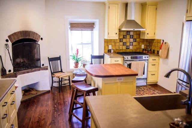 Photo of a small traditional u-shaped separate kitchen in Albuquerque with a farmhouse sink, shaker cabinets, yellow cabinets, concrete benchtops, yellow splashback, ceramic splashback, stainless steel appliances, dark hardwood floors, with island and brown floor.