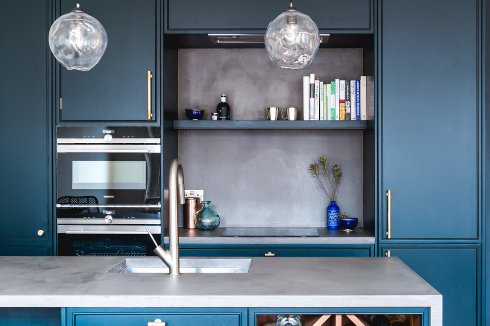 Design ideas for a small eclectic single-wall open plan kitchen in London with an undermount sink, flat-panel cabinets, blue cabinets, concrete benchtops, black appliances, dark hardwood floors, with island and brown floor.