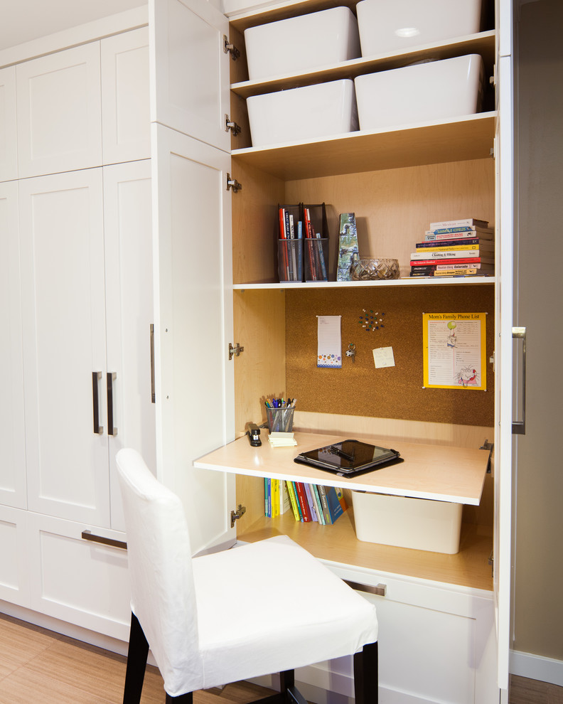 Photo of a small transitional home office in Vancouver with a built-in desk and light hardwood floors.