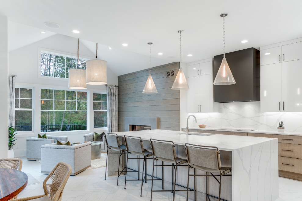 Photo of a large contemporary galley open plan kitchen in Grand Rapids with an undermount sink, flat-panel cabinets, light wood cabinets, white splashback, panelled appliances, with island, white floor and white benchtop.