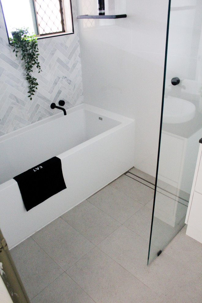 This is an example of a small modern kids bathroom in Perth with flat-panel cabinets, white cabinets, a freestanding tub, an open shower, a one-piece toilet, white tile, ceramic tile, white walls, porcelain floors, a vessel sink, engineered quartz benchtops, grey floor, an open shower and black benchtops.
