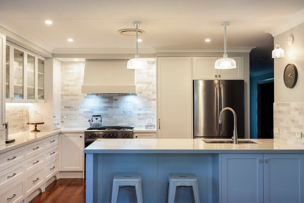 Inspiration for a classic u-shaped open plan kitchen in Newcastle - Maitland with a double-bowl sink, shaker cabinets, white cabinets, engineered stone countertops, multi-coloured splashback, marble splashback, stainless steel appliances, medium hardwood flooring, a breakfast bar, brown floors and beige worktops.