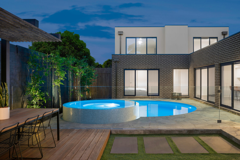 Contemporary backyard round pool in Melbourne with a hot tub and stamped concrete.