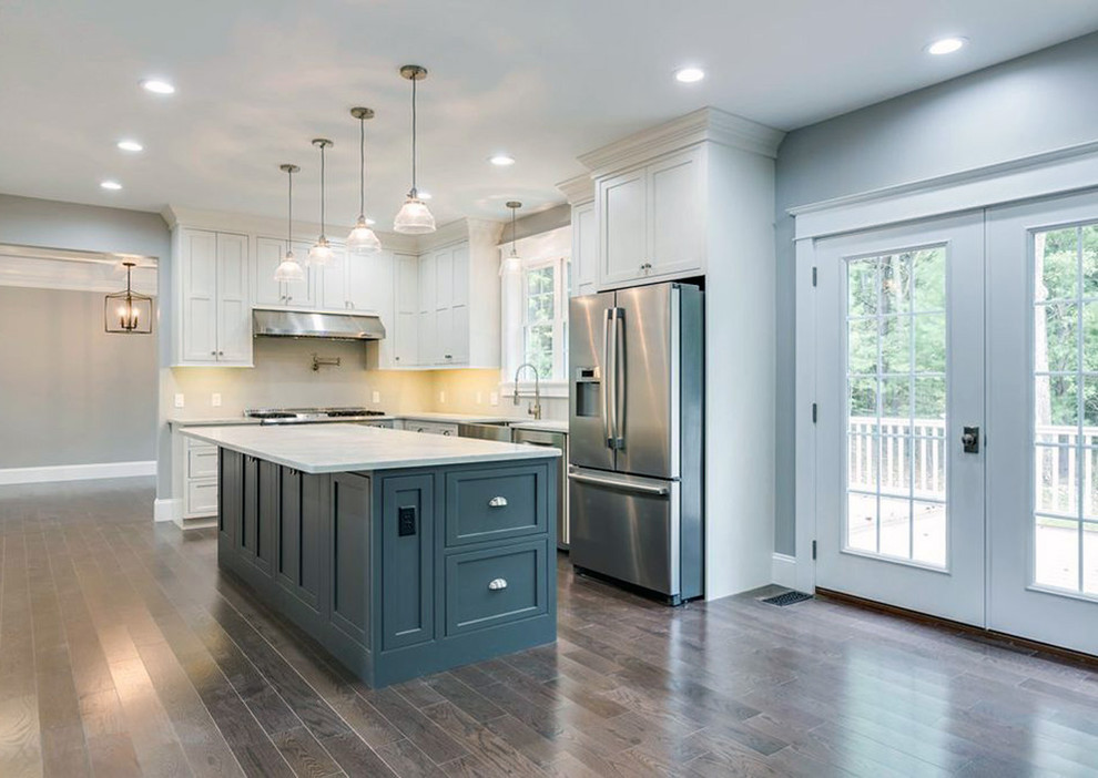 Large transitional l-shaped dark wood floor and brown floor kitchen pantry photo with a farmhouse sink, recessed-panel cabinets, white cabinets, quartz countertops, stainless steel appliances, an island and white countertops