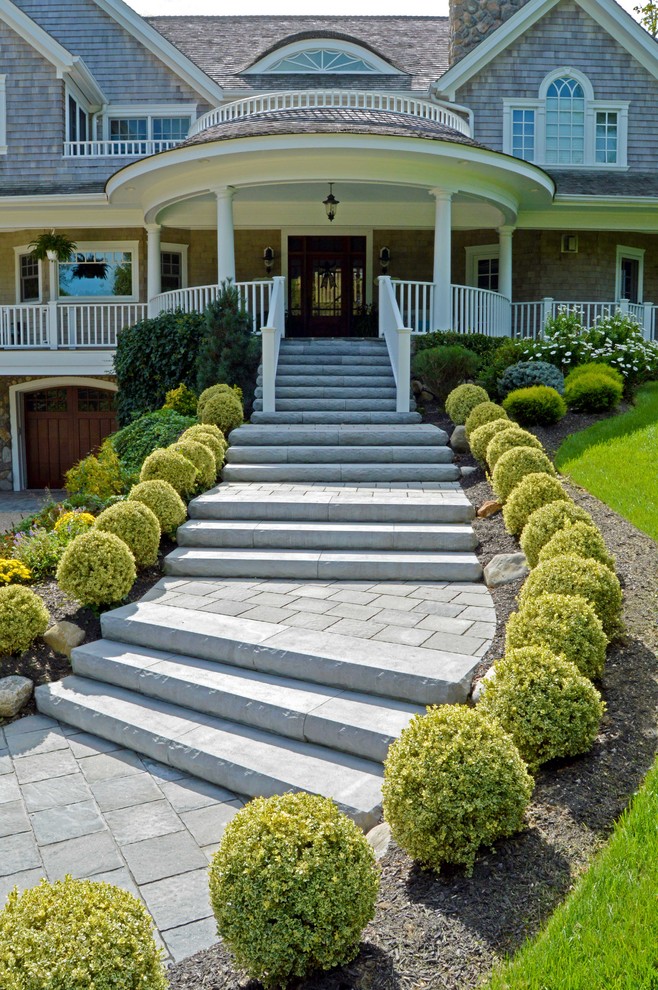 This is an example of a mid-sized beach style front yard driveway in New York with natural stone pavers.