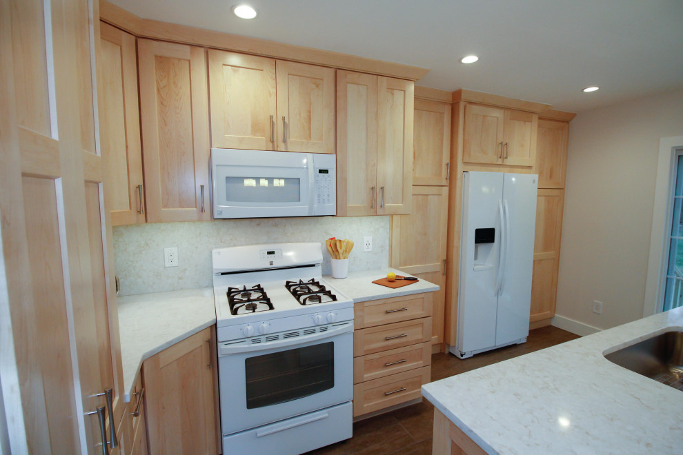 This is an example of a mid-sized contemporary l-shaped eat-in kitchen in Newark with an undermount sink, shaker cabinets, light wood cabinets, quartz benchtops, white splashback, white appliances, porcelain floors, with island, brown floor and white benchtop.