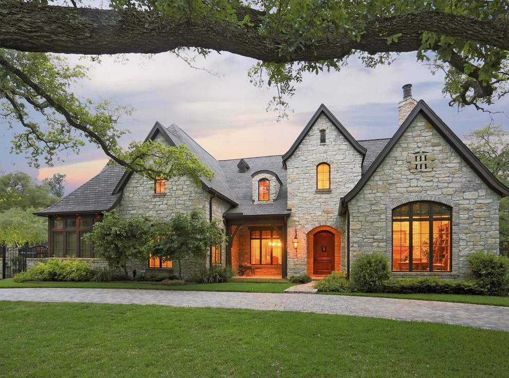 Design ideas for a large traditional two-storey grey exterior in Houston with stone veneer and a gable roof.