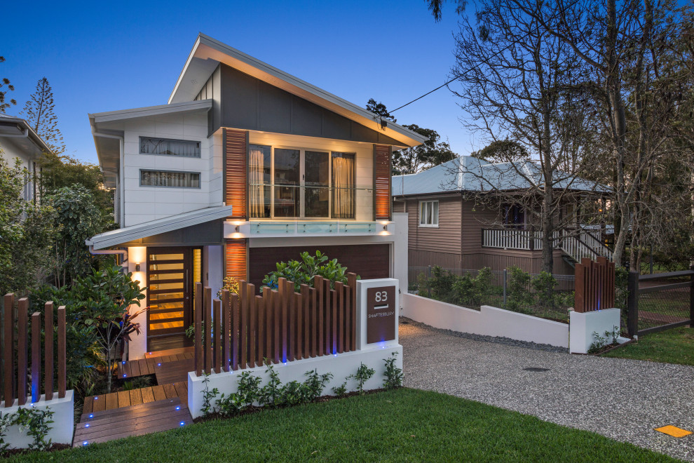 Photo of a mid-sized two-storey white house exterior in Brisbane with concrete fiberboard siding, a butterfly roof and a metal roof.