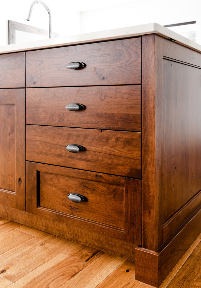 Inspiration for a mid-sized transitional l-shaped medium tone wood floor and brown floor kitchen pantry remodel with an undermount sink, shaker cabinets, white cabinets, quartzite countertops, gray backsplash, porcelain backsplash, stainless steel appliances, an island and white countertops