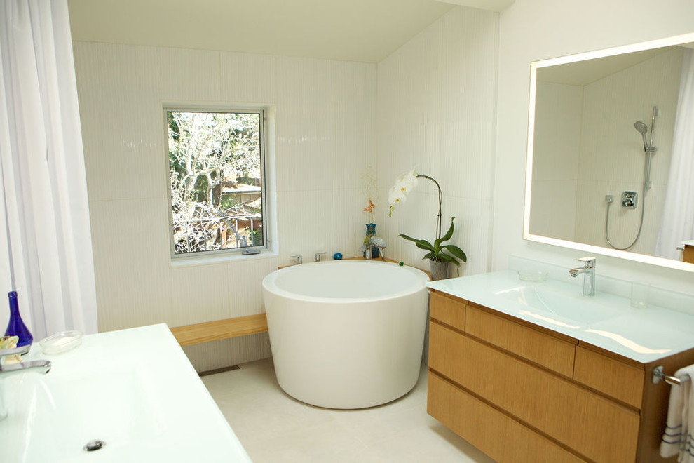 Design ideas for a large master bathroom in San Francisco with flat-panel cabinets, light wood cabinets, a japanese tub, a curbless shower, a one-piece toilet, white tile, ceramic tile, white walls, ceramic floors, an integrated sink, recycled glass benchtops, white floor, a shower curtain and white benchtops.