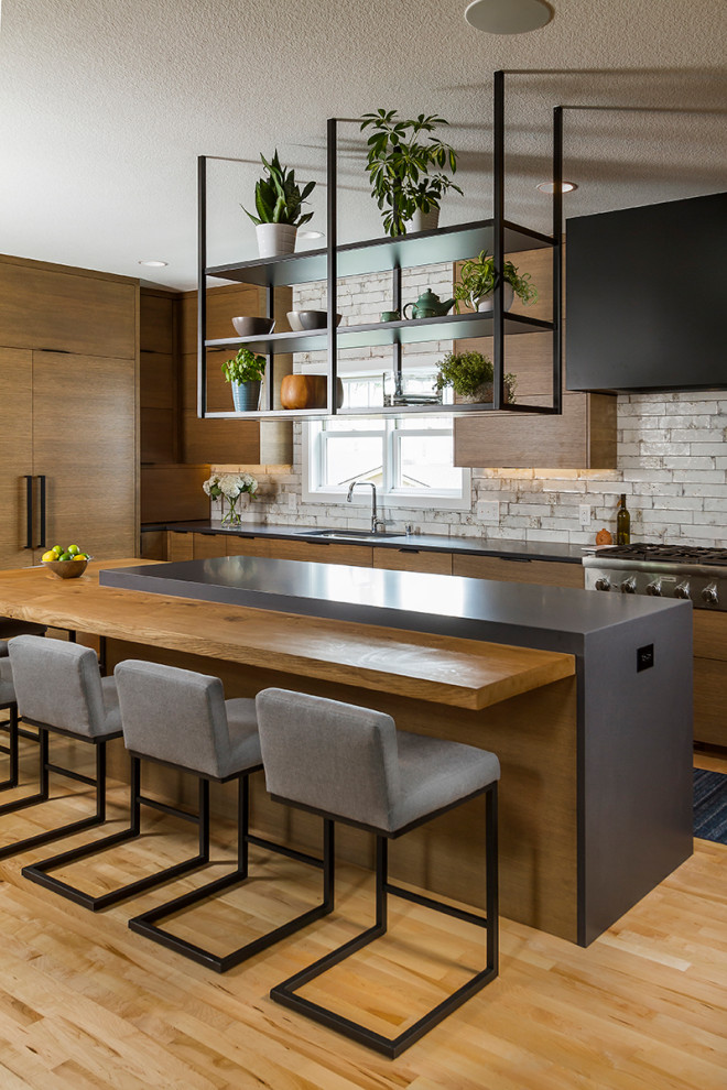 Inspiration for a modern eat-in kitchen in Minneapolis with an undermount sink, flat-panel cabinets, brown cabinets, solid surface benchtops, white splashback, ceramic splashback, stainless steel appliances, light hardwood floors, with island and black benchtop.