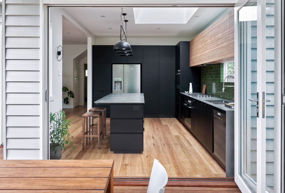 Inspiration for a mid-sized contemporary l-shaped eat-in kitchen in Melbourne with an undermount sink, flat-panel cabinets, black cabinets, laminate benchtops, green splashback, porcelain splashback, stainless steel appliances, light hardwood floors, with island and grey benchtop.