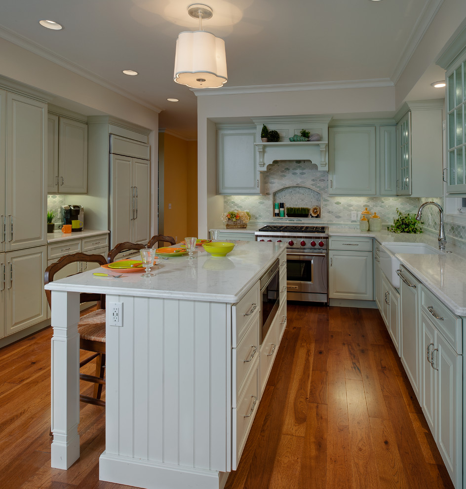 Inspiration for a mid-sized transitional l-shaped eat-in kitchen in Other with a farmhouse sink, green cabinets, quartz benchtops, green splashback, mosaic tile splashback, stainless steel appliances, medium hardwood floors, with island, recessed-panel cabinets and brown floor.