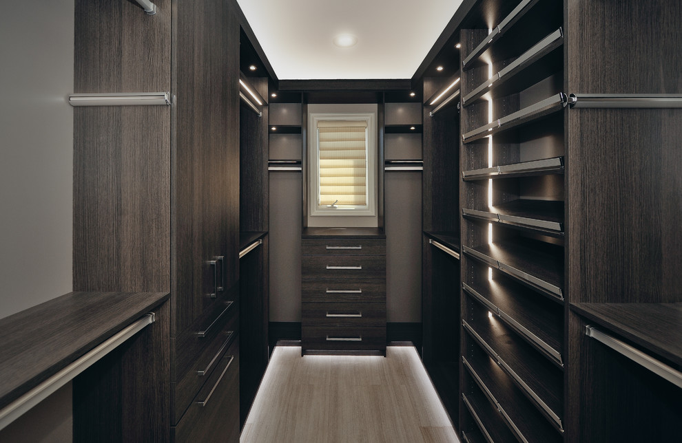 This is an example of a mid-sized arts and crafts men's walk-in wardrobe in Orange County with flat-panel cabinets, grey cabinets, light hardwood floors and beige floor.
