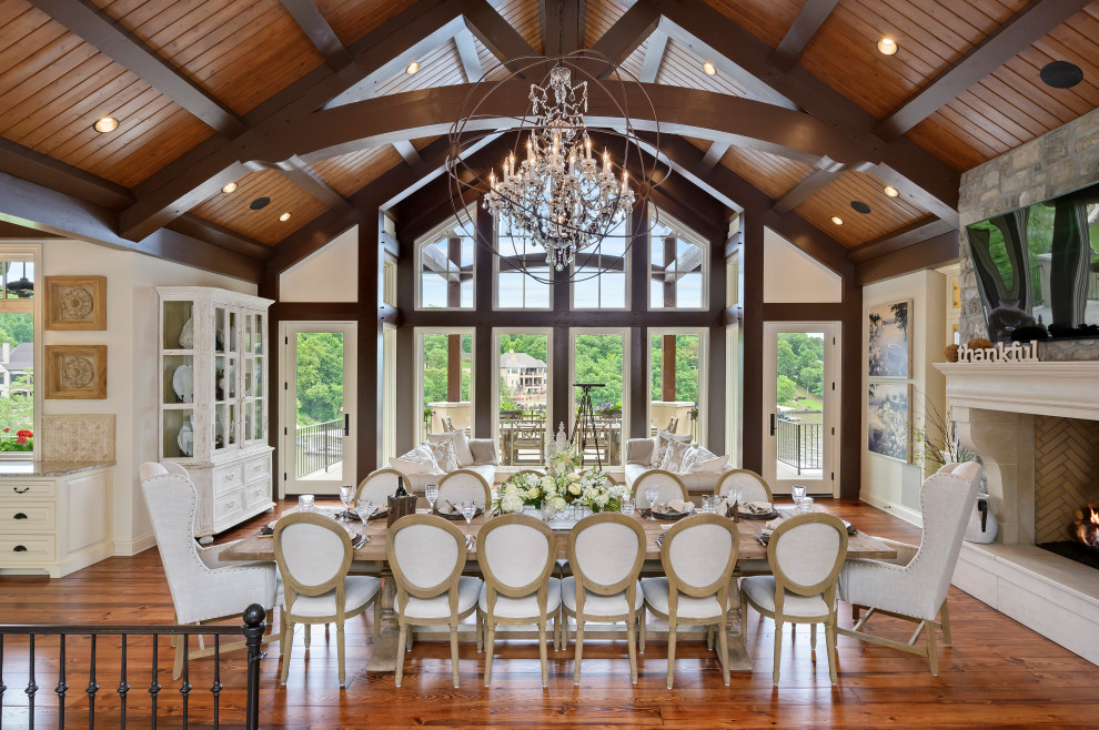 Expansive mediterranean open plan dining in Kansas City with white walls, medium hardwood floors, a standard fireplace, a stone fireplace surround and brown floor.