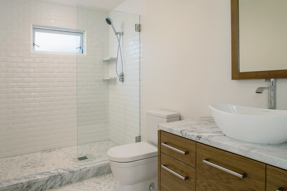 Inspiration for a modern bathroom in San Francisco with a vessel sink, flat-panel cabinets, medium wood cabinets, marble benchtops, a freestanding tub, an alcove shower, white tile, porcelain tile, white walls and marble floors.