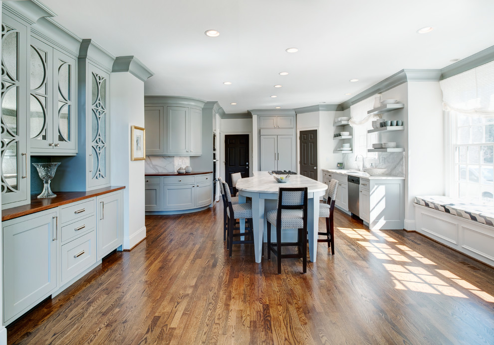 Mid-sized transitional l-shaped medium tone wood floor open concept kitchen photo in Atlanta with recessed-panel cabinets, marble countertops, white backsplash, paneled appliances and an island