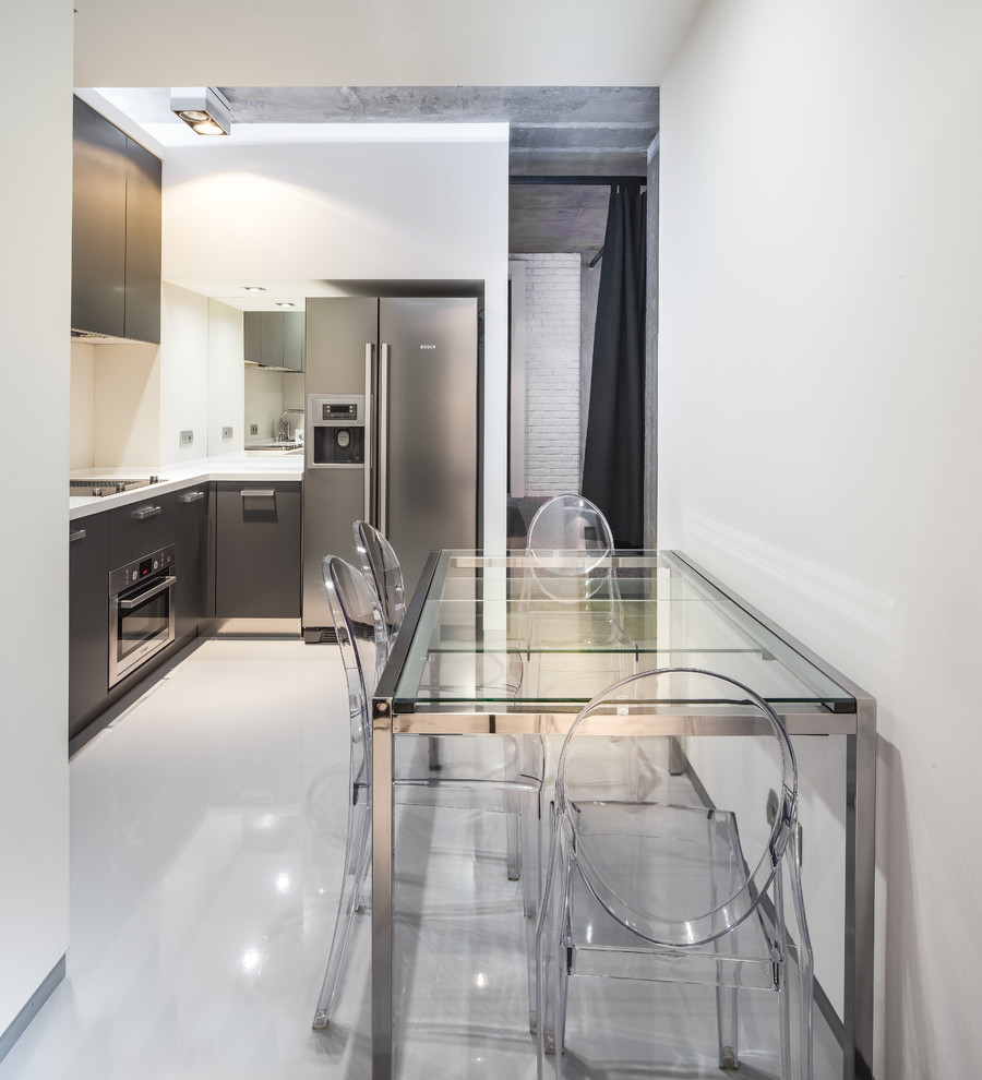 Small contemporary l-shaped eat-in kitchen in Yekaterinburg with flat-panel cabinets, grey cabinets, stainless steel appliances, concrete floors, grey floor, white benchtop and white splashback.