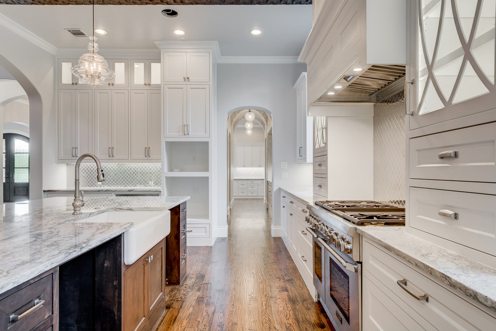 Mid-sized transitional single-wall separate kitchen in Dallas with a farmhouse sink, white cabinets, granite benchtops, metal splashback, stainless steel appliances, dark hardwood floors, with island, recessed-panel cabinets and metallic splashback.