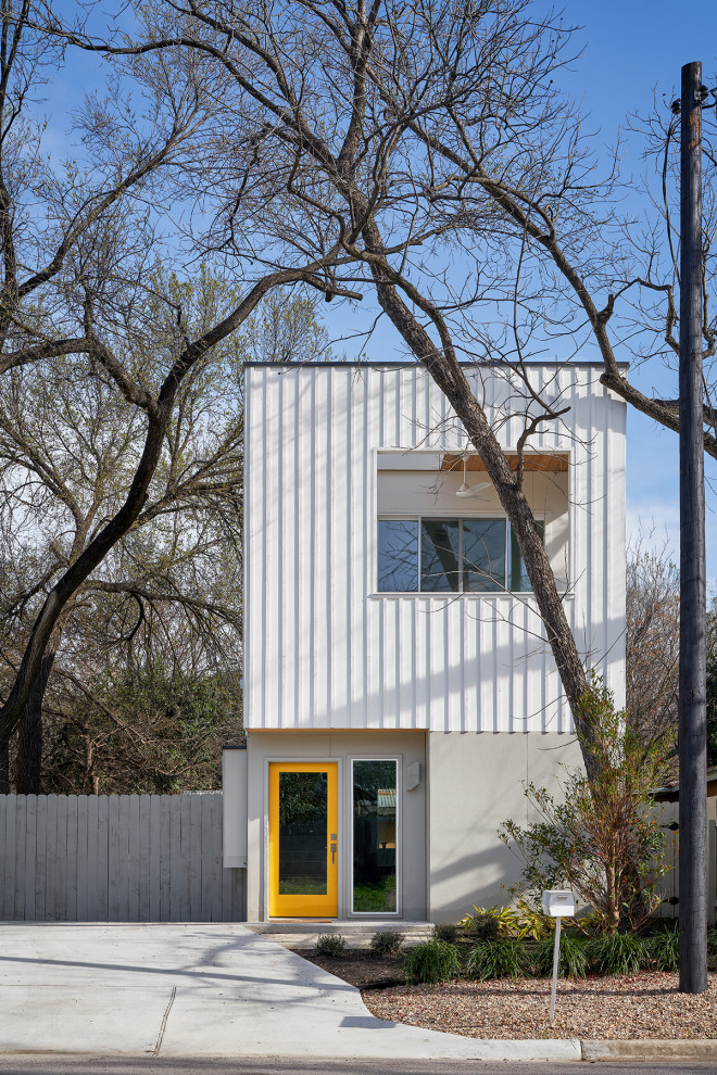 Small midcentury two-storey white house exterior in Austin with concrete fiberboard siding and a flat roof.