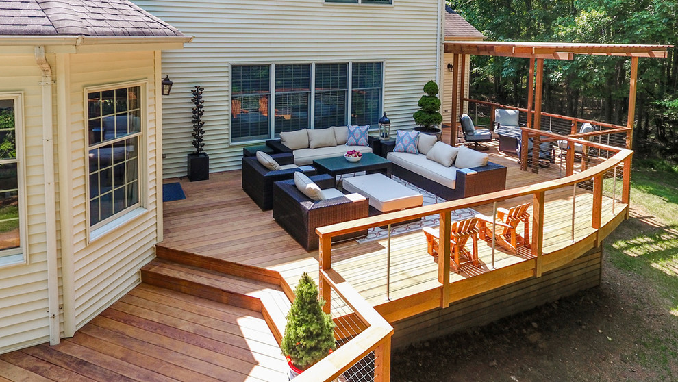 Photo of an expansive transitional backyard deck in Other with a fire feature and a pergola.