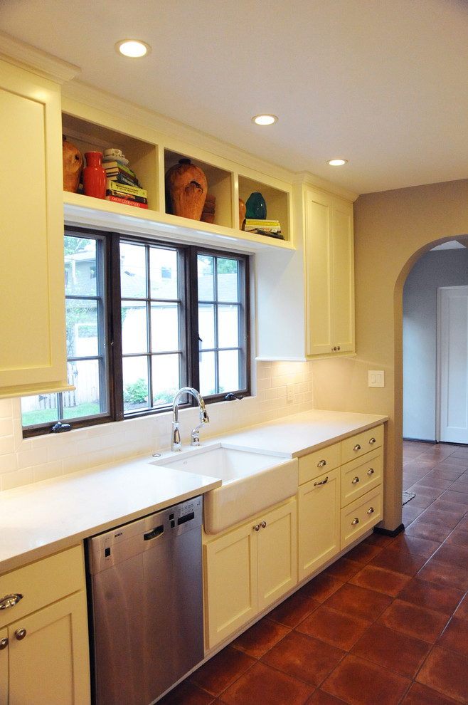 This is an example of a mid-sized traditional galley separate kitchen in Orange County with a farmhouse sink, shaker cabinets, white cabinets, quartz benchtops, white splashback, subway tile splashback, stainless steel appliances, ceramic floors and no island.