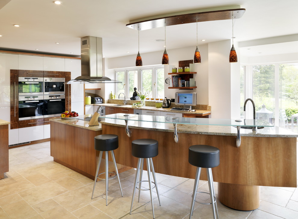 This is an example of a large contemporary open plan kitchen in Cambridgeshire with an undermount sink, flat-panel cabinets, white cabinets, granite benchtops, stainless steel appliances, ceramic floors and with island.