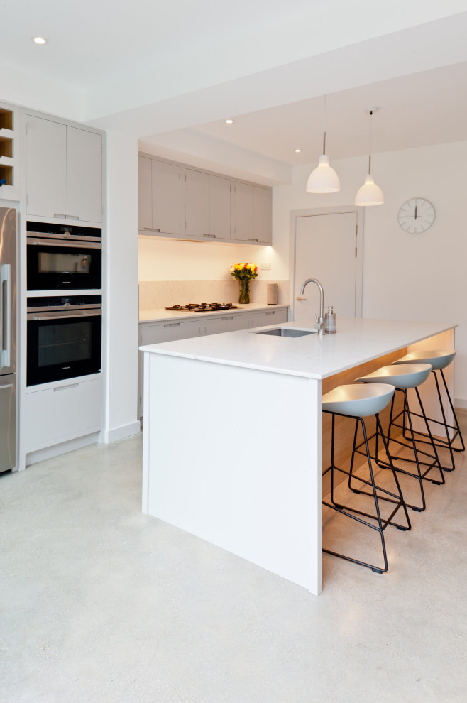 Design ideas for a large contemporary galley kitchen in London with an undermount sink, flat-panel cabinets, grey cabinets, beige splashback, porcelain splashback, stainless steel appliances, porcelain floors, with island, grey floor and white benchtop.