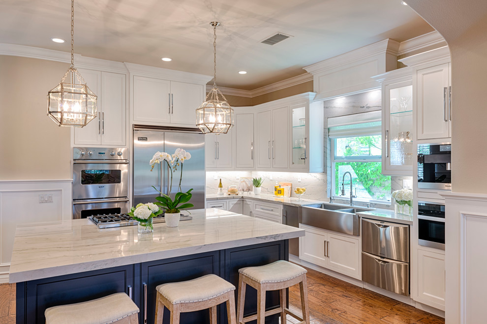 Large transitional l-shaped medium tone wood floor eat-in kitchen photo in Orange County with a drop-in sink, quartzite countertops, white backsplash, stone slab backsplash, stainless steel appliances, an island, beaded inset cabinets and white cabinets