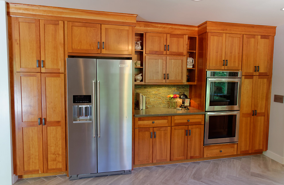 This is an example of an expansive arts and crafts u-shaped eat-in kitchen in Seattle with an integrated sink, shaker cabinets, medium wood cabinets, solid surface benchtops, green splashback, stone tile splashback, stainless steel appliances, porcelain floors and with island.