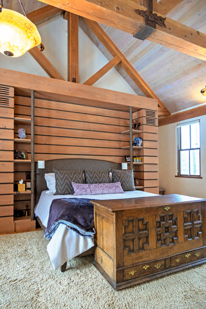 Inspiration pour une grande chambre parentale chalet avec un mur beige, parquet clair, une cheminée standard, un manteau de cheminée en pierre et un plafond voûté.