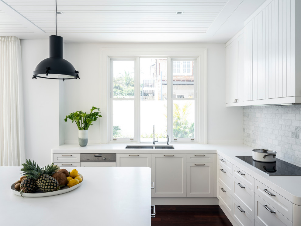 Design ideas for a contemporary open plan kitchen in Sydney with an undermount sink, shaker cabinets, white cabinets, solid surface benchtops, grey splashback, marble splashback, panelled appliances, dark hardwood floors, with island, brown floor, white benchtop and wood.