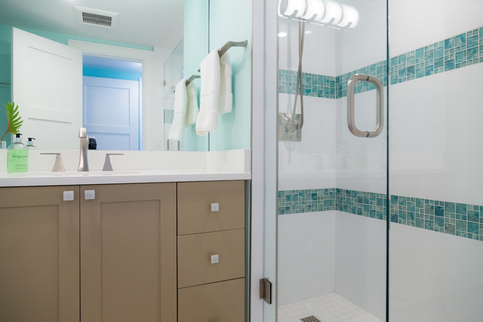 Cette image montre une douche en alcôve principale marine avec un placard à porte shaker, des portes de placard beiges, un carrelage multicolore, un carrelage en pâte de verre, un mur bleu, un lavabo encastré et une cabine de douche à porte battante.