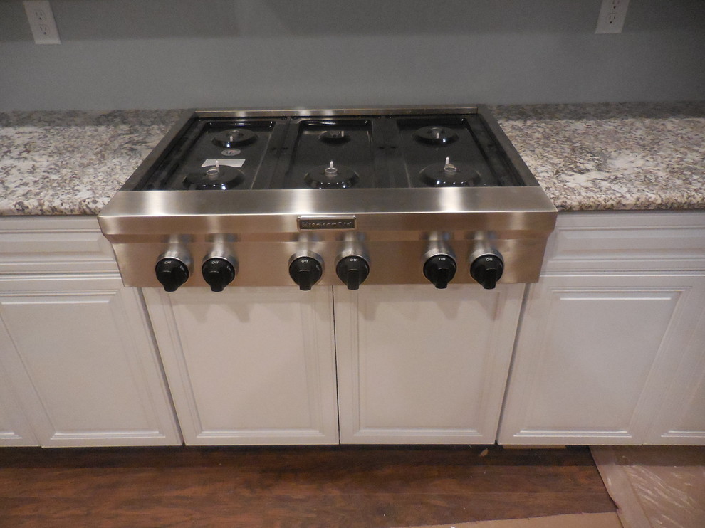 Inspiration for a mid-sized transitional u-shaped medium tone wood floor kitchen remodel in Baltimore with an undermount sink, raised-panel cabinets, white cabinets, granite countertops and stainless steel appliances
